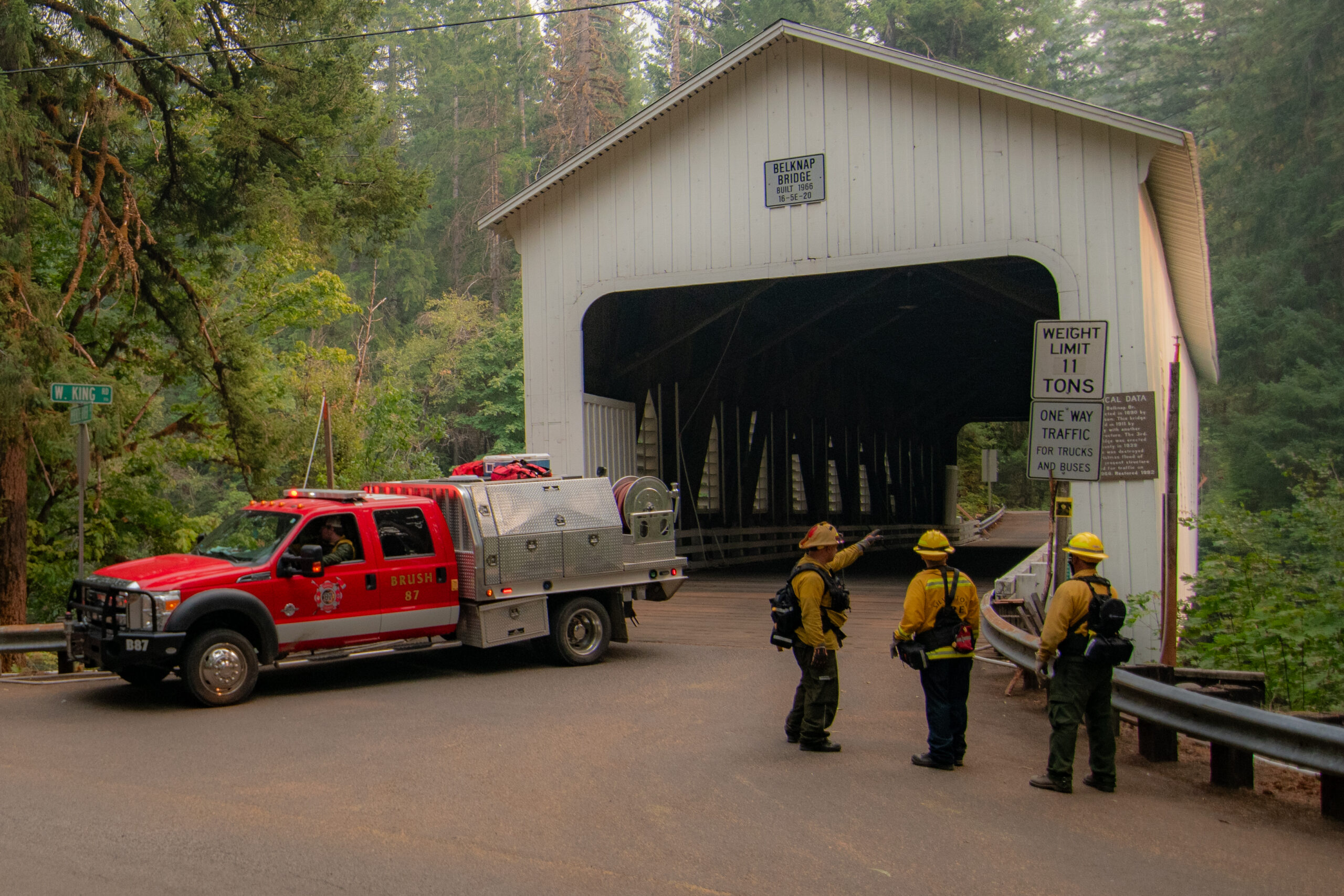 Three firefighters standing outside of a covered bridge near the Lookout Fire in Lane County