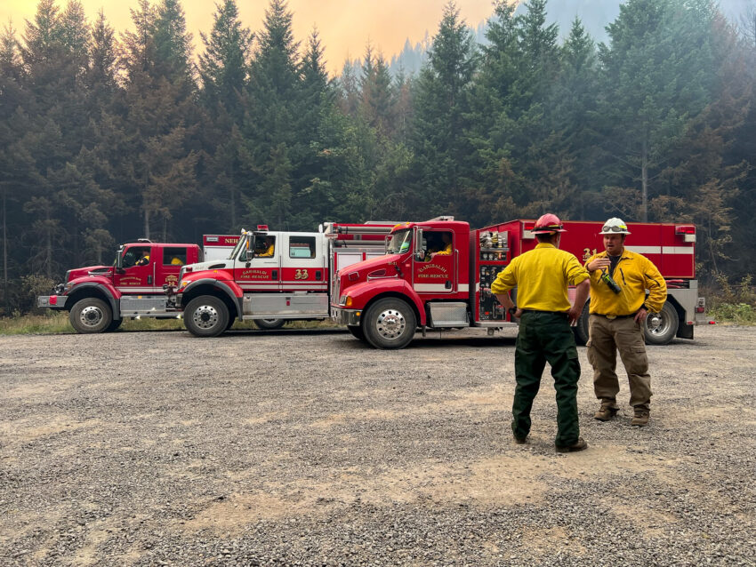 Two firefighters standing in front of three fire engines on the Lookout Fire in Lane County Oregon