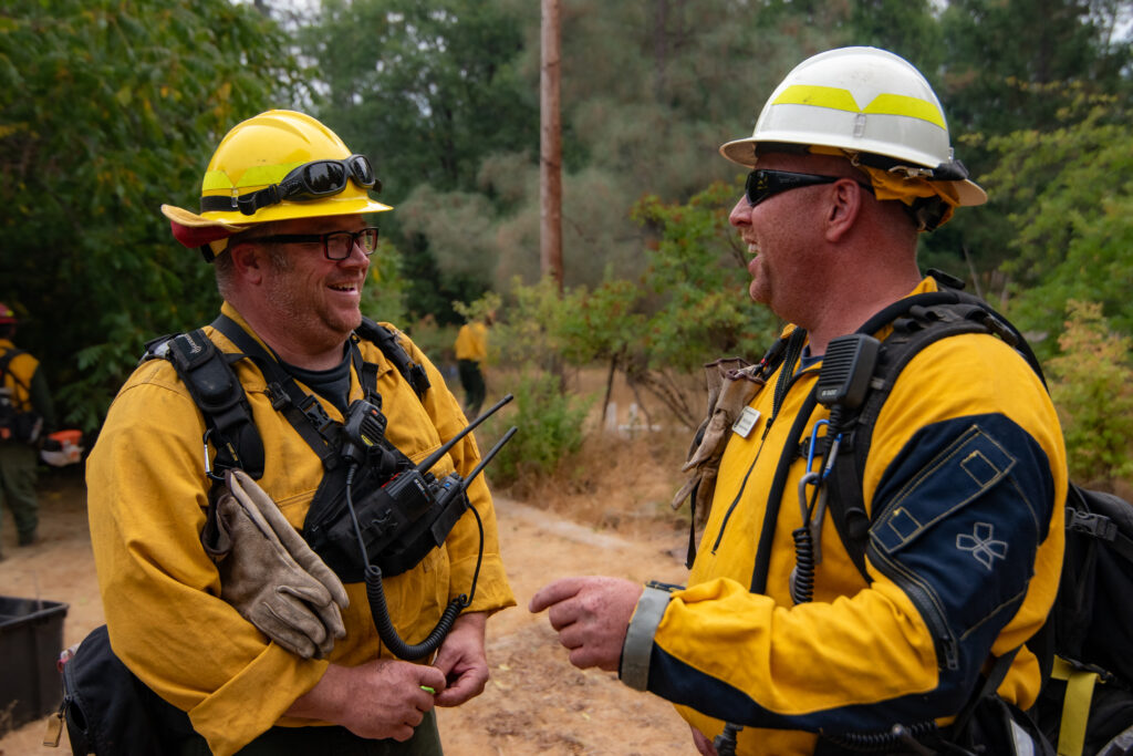 Two firefighters smiling at each other.