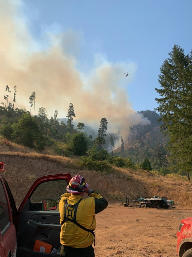 A firefighter watching a helicopter drop water on a wildfire on the Tyee Ridge Complex in Douglas County Oregon 