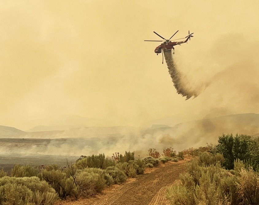 A helicopter dropping water on the Cow Valley Fire