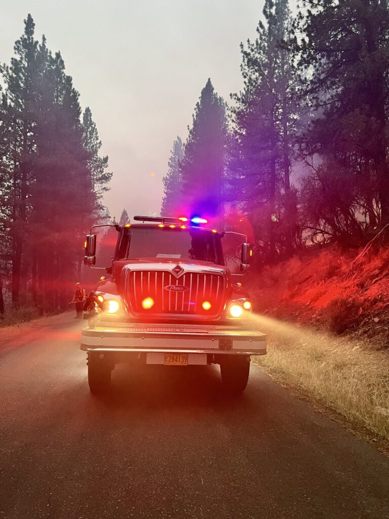 A fire engine parked with lights flashing on the Falls Fire