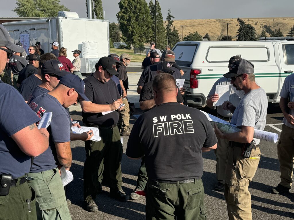 Firefighters standing during a morning briefing on the larch creek fire.