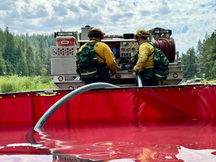 firefighters near a fire engine and a water tank