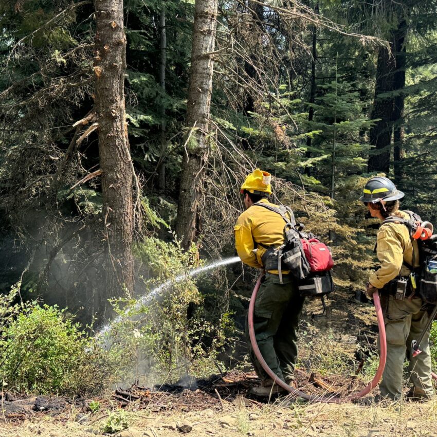 Two firefighters putting water on the Lone Rock Fire.