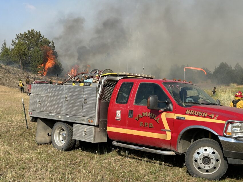 A fire engine parked with firefighters working to stop a fire.