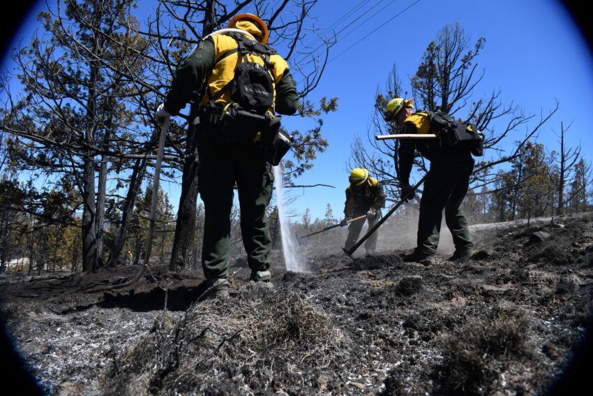 Three firefighters shoot water and dig line on the Highland Fire.