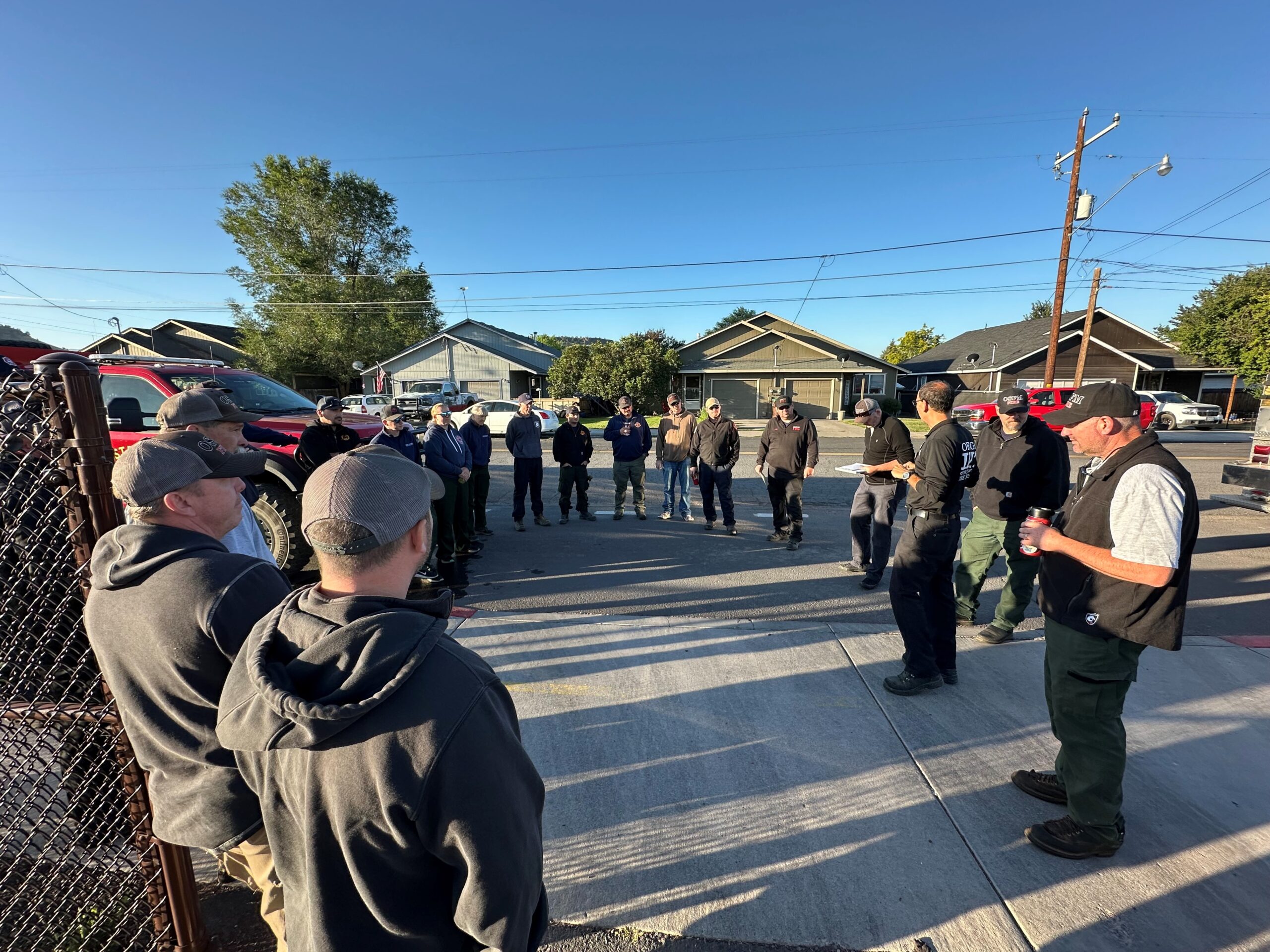 Fire personnel stand in a large circle as they share fire information.
