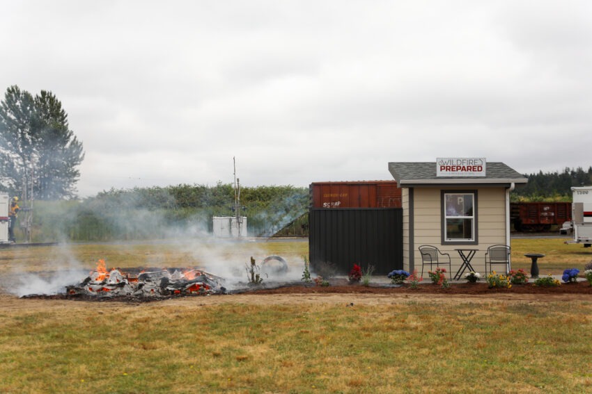 A house on the left is burned completely while a house on the right stands with minimal damage.